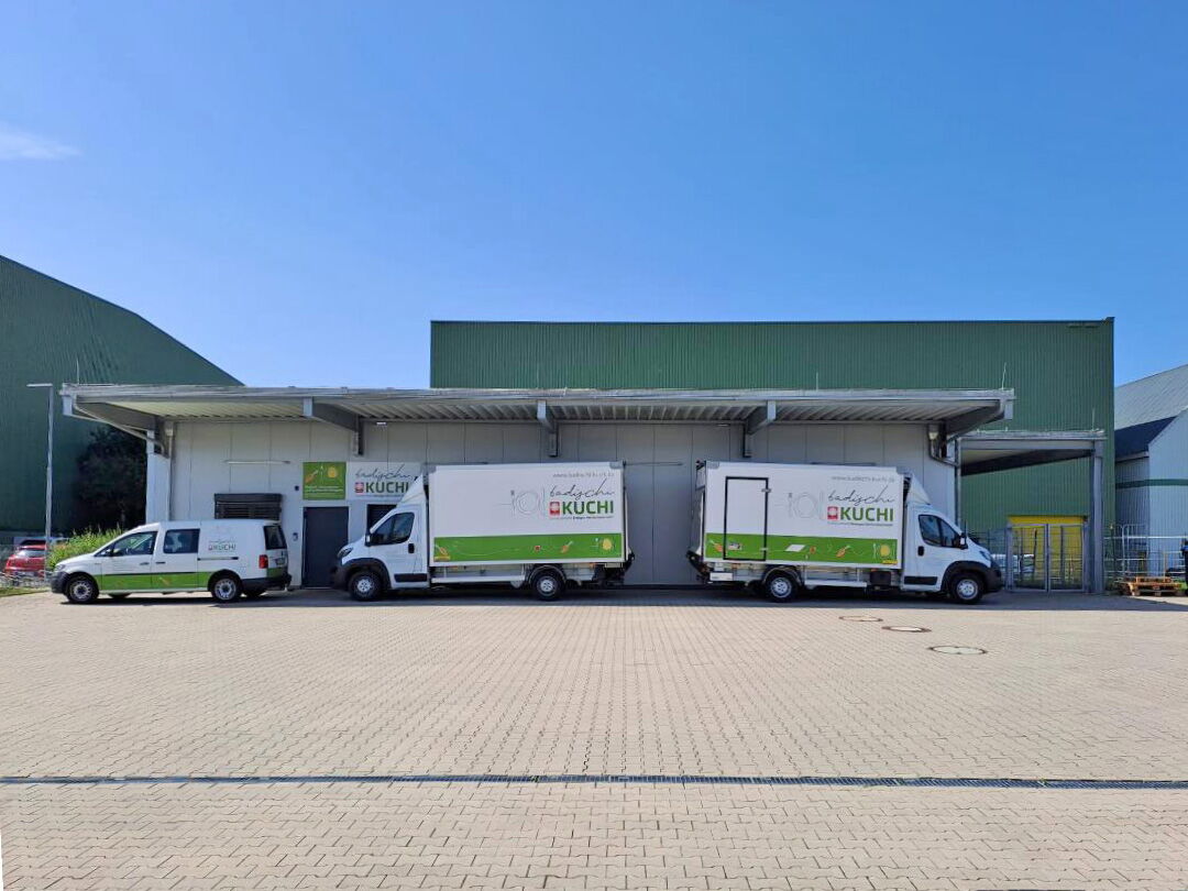 Firmengelände mit drei Lieferwägen mit „badischi Kuchi“-Logo
